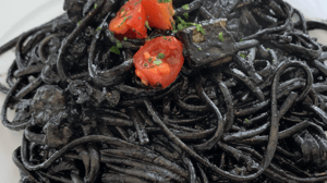 Black noodles on a platae topped with tomato Black noodles on a platae topped with tomato