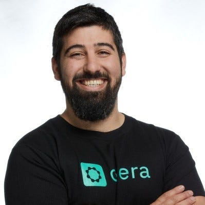 Yotam Segev, Co-Founder and CEO of Cyera, wears a thick black beard, a black Cyera t-shirt, and a wide smile