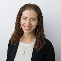 Marina Kaganovich has long brown curly hair and is a wearing a white shirt and black sweater over it Marina Kaganovich has long brown curly hair and is a wearing a white shirt and black sweater over it