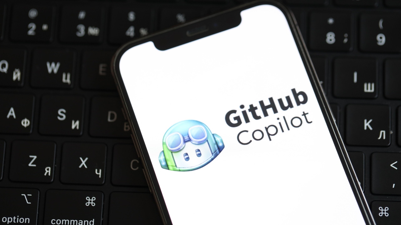 GitHub Copilot's logo on an iPhone screen, laying on a keyboard GitHub Copilot's logo on an iPhone screen, laying on a keyboard