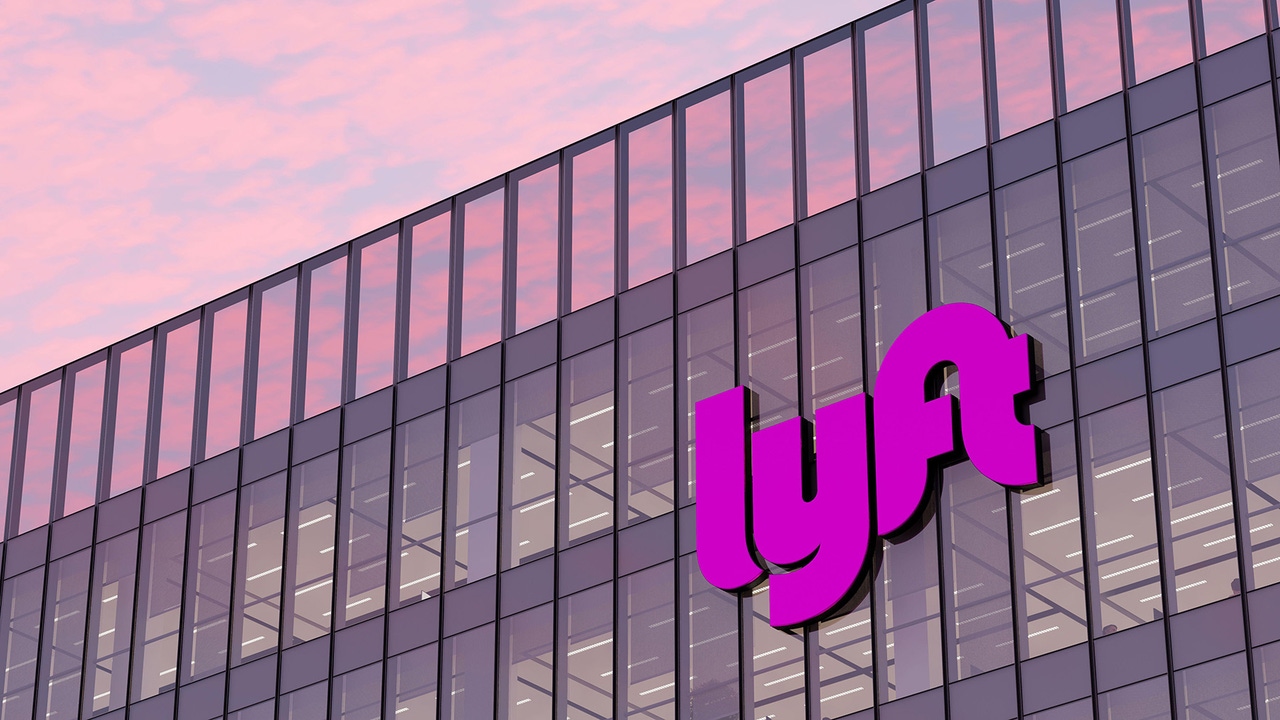 Lyft Signage Logo on Top of Glass Building. Workplace Transport Company Office lit by pink sunset. Lyft Signage Logo on Top of Glass Building. Workplace Transport Company Office lit by pink sunset.