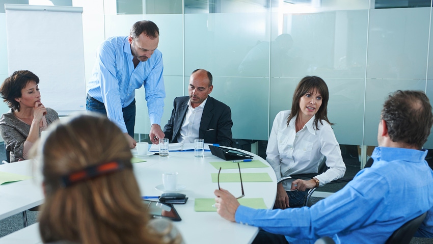 Businessmen and women chatting around boardroom table