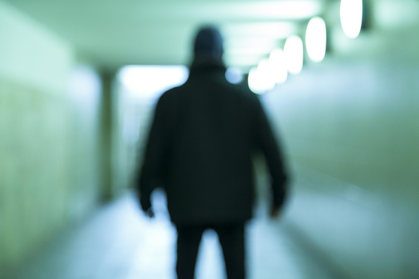 Blurred figure in a hoodie standing in a tunnel
