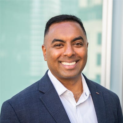Resilience CEO Vishaal Hariprasad has black hair worn in a military-style crew cut; he wears a blue jacket over a white oxford