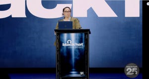 Journalist Kim Zetter stands at a podium at Black Hat USA 2022. Her hair is pulled back, and she's wearing glasses.