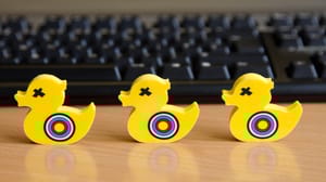 Three yellow plastic ducks with targets painted on them in front of a keyboard Three yellow plastic ducks with targets painted on them in front of a keyboard