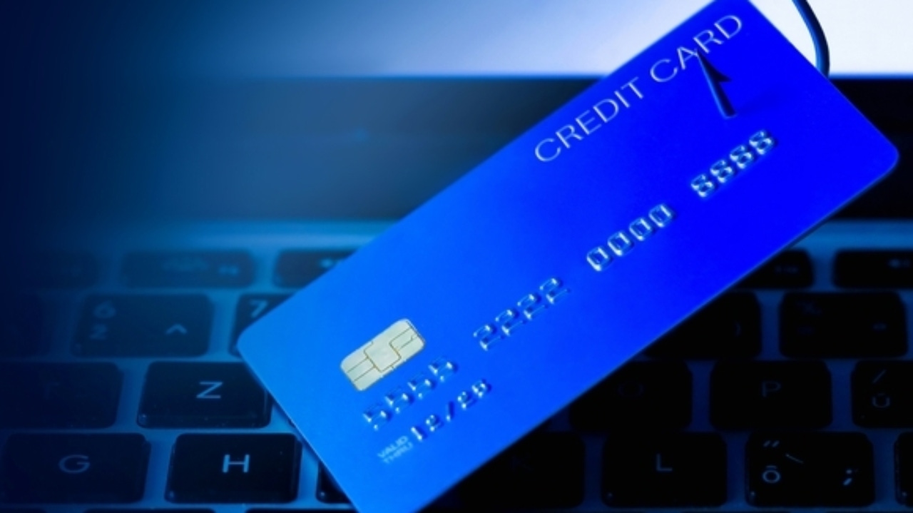 A blue credit card on a fish hook being dangled above a computer keyboard A blue credit card on a fish hook being dangled above a computer keyboard