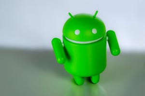 Image shows a green robot that has become known as the icon for Google's Android mobile OS against a blurred background