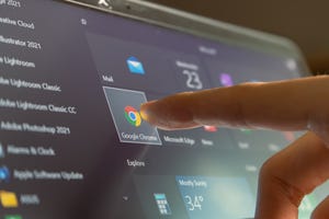 Finger touching Google Chrome icon on computer screen