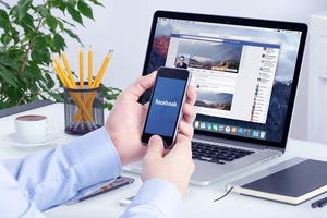 Hand holding mobile device and loading Facebook.