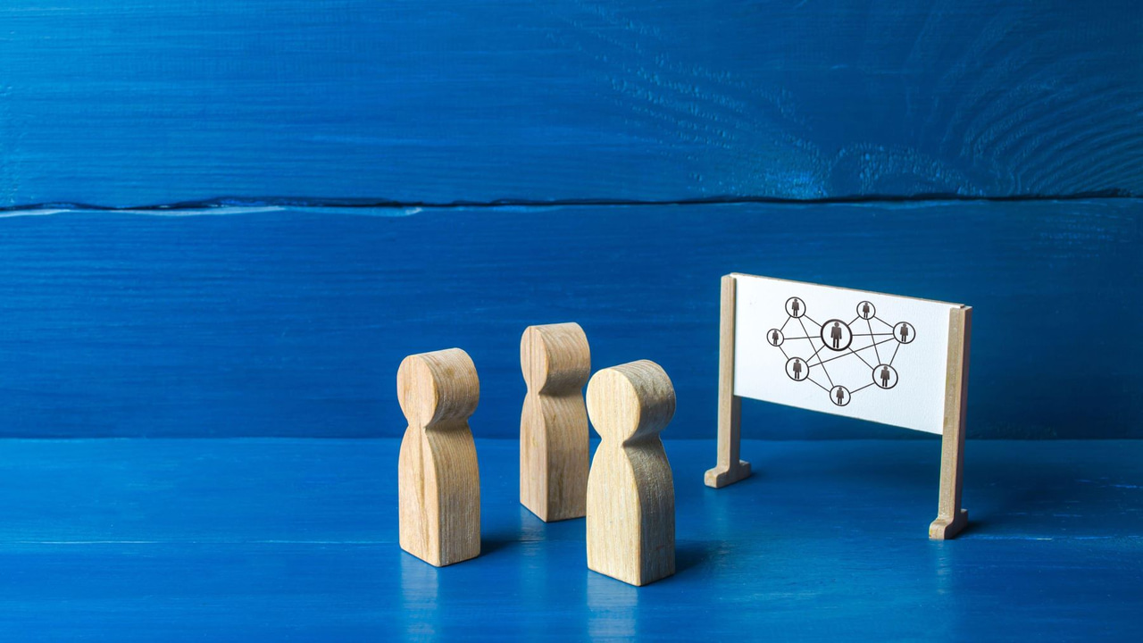 Three wooden figures representing people in front of a whiteboard Three wooden figures representing people in front of a whiteboard