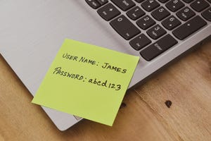 A yellow Postit note stuck to a laptop showing a username "James"and a password "abcd123"