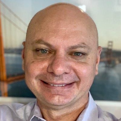 Tim Van Ash, SVP of Products and Technology at AutoRABIT, who has a shaved head and blue eyes, smiles in a collared shirt.