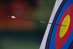 An arrow sticks out of the bullseye center of an archery target