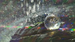 A crystal ball sits in a water fountain, water drops and rainbow rays shooting everywhere A crystal ball sits in a water fountain, water drops and rainbow rays shooting everywhere