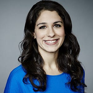 Julianne Pepitone, a white woman with long dark hair and dark eyes, smiles while wearing a blue sweater.
