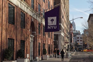 New York University buildings with purple NYU logo flag hanging outside the entrance and Empire State Building in background