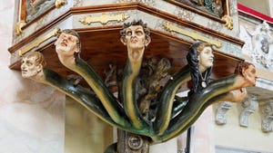 Pulpit of the Seven Deadly Sins in Austria, where human heads are carved onto a seven-headed serpent