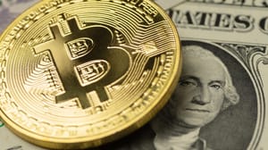 A physical representation of a bitcoin covering a US dollar bill A physical representation of a bitcoin covering a US dollar bill