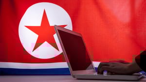 A laptop in front of a DPRK flag A laptop in front of a DPRK flag