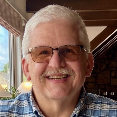 Patrick Barnett, Principal Consultant at Secureworks, has short graying hair and a mustache. He smiles, wearing a tuxedo.