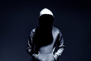 Image shows person in a hooded sweatshirt with face covered by a shadow in a dark backdrop