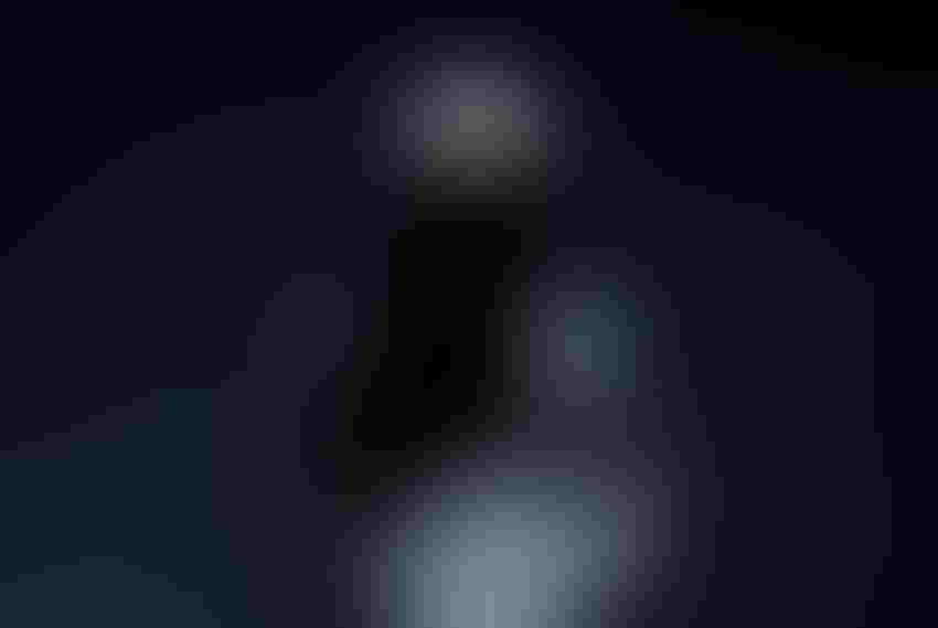 a hooded figure in darkened lighting.