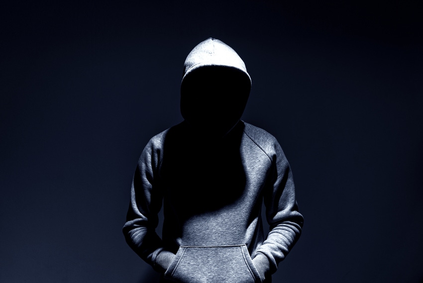 Image shows person in a hooded sweatshirt with face obscured by a shadow against a dark background