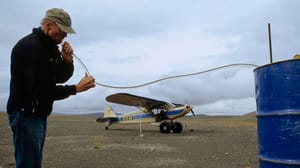 A small aircraft pilot siphons gas from a tank; North Slope, Alaska A small aircraft pilot siphons gas from a tank; North Slope, Alaska