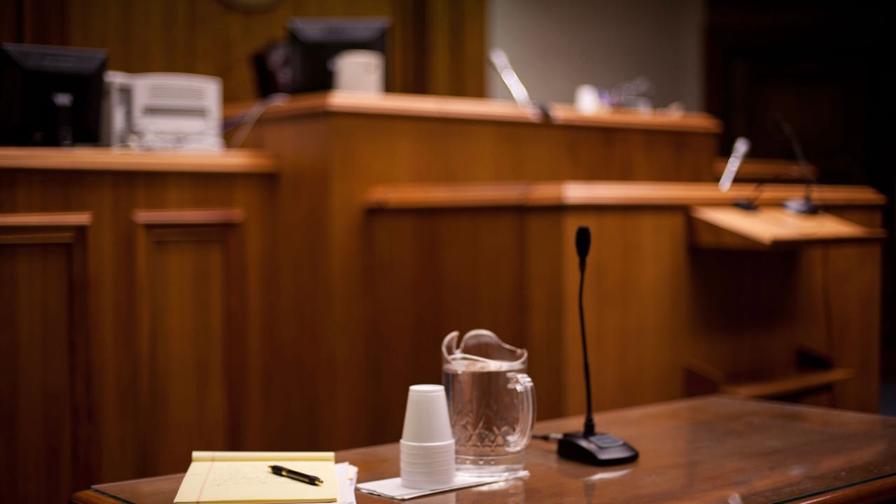裁判官席の前の裁判所の机の上にある紙、ペン、カップ、水 裁判官席の前の裁判所の机の上にある紙、ペン、カップ、水