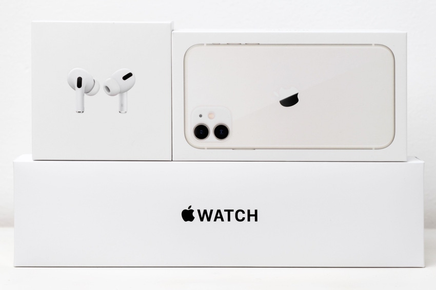Apple products including AirPods, iPhone and Apple Watch stacked neatly on white background