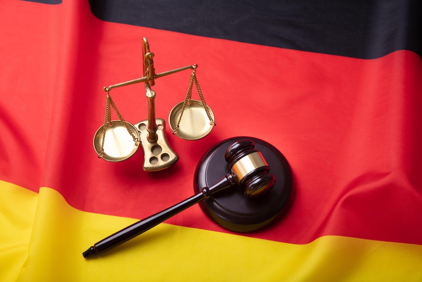 A judge's gavel and scales of justice on a German flag