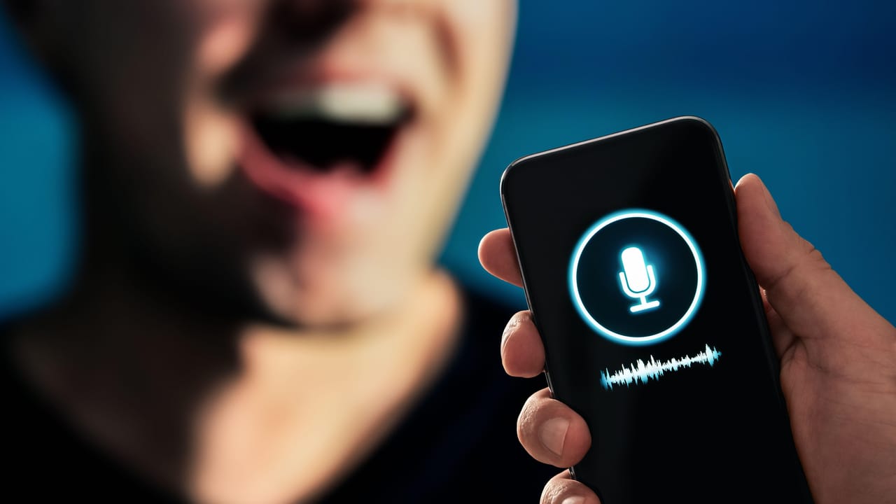 音声生成アプリを表示したモバイルデバイスに話しかける男性 音声生成アプリを表示したモバイルデバイスに話しかける男性