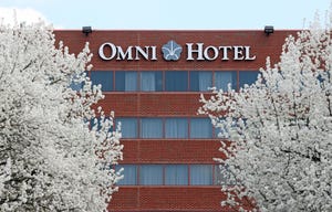Omni Hotel with two blossoming trees on either side of the hotel logo on the building