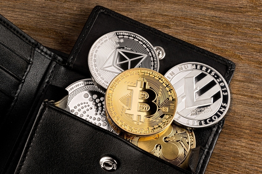 Cryptocurrency coins in leather wallet on wooden background