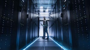 Blurry person standing between server racks in a data center Blurry person standing between server racks in a data center