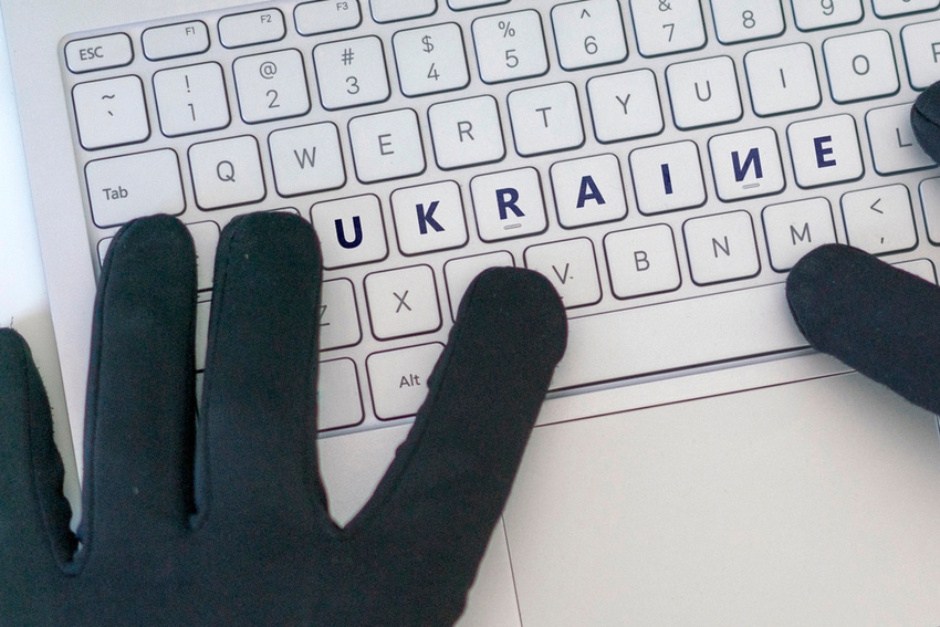 Dark gloved hands depicting a cybercriminal typing UKRAINE on a keyboard