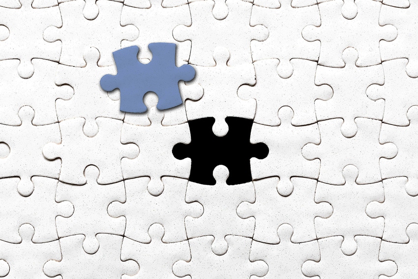 Photo of white blank jigsaw puzzle with one piece taken out and a matching blue piece sitting on top