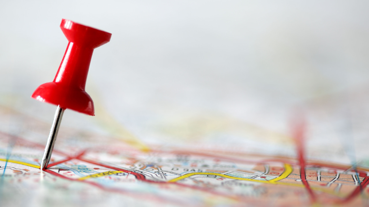 A red pushpin pinpointing a location on a map A red pushpin pinpointing a location on a map