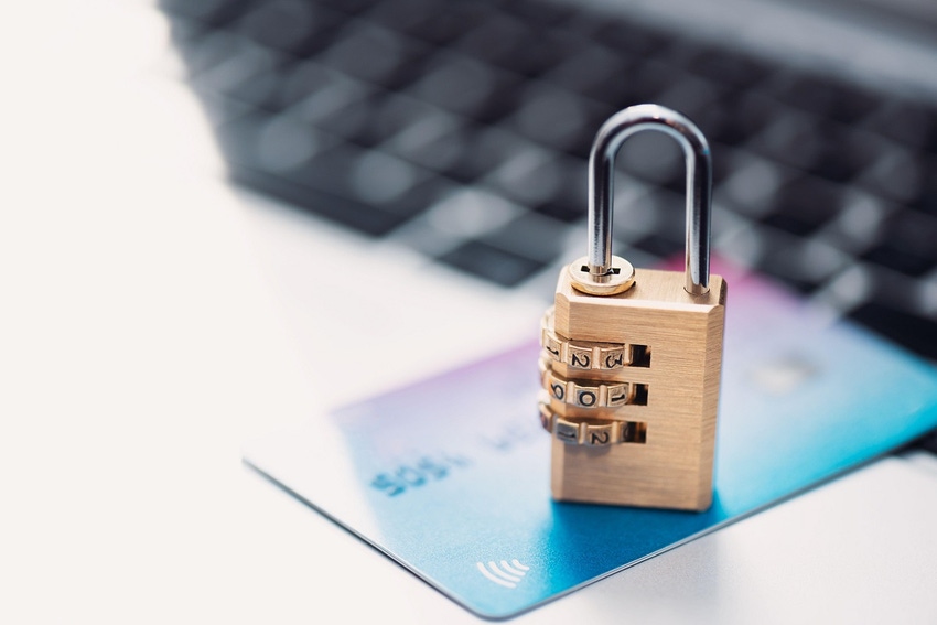 Small padlock sitting on a credit card with keyboard in background