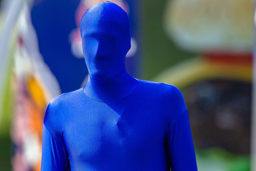 Blue man head to feet covered in full Lycra body suite material outdoors event closeup photo.