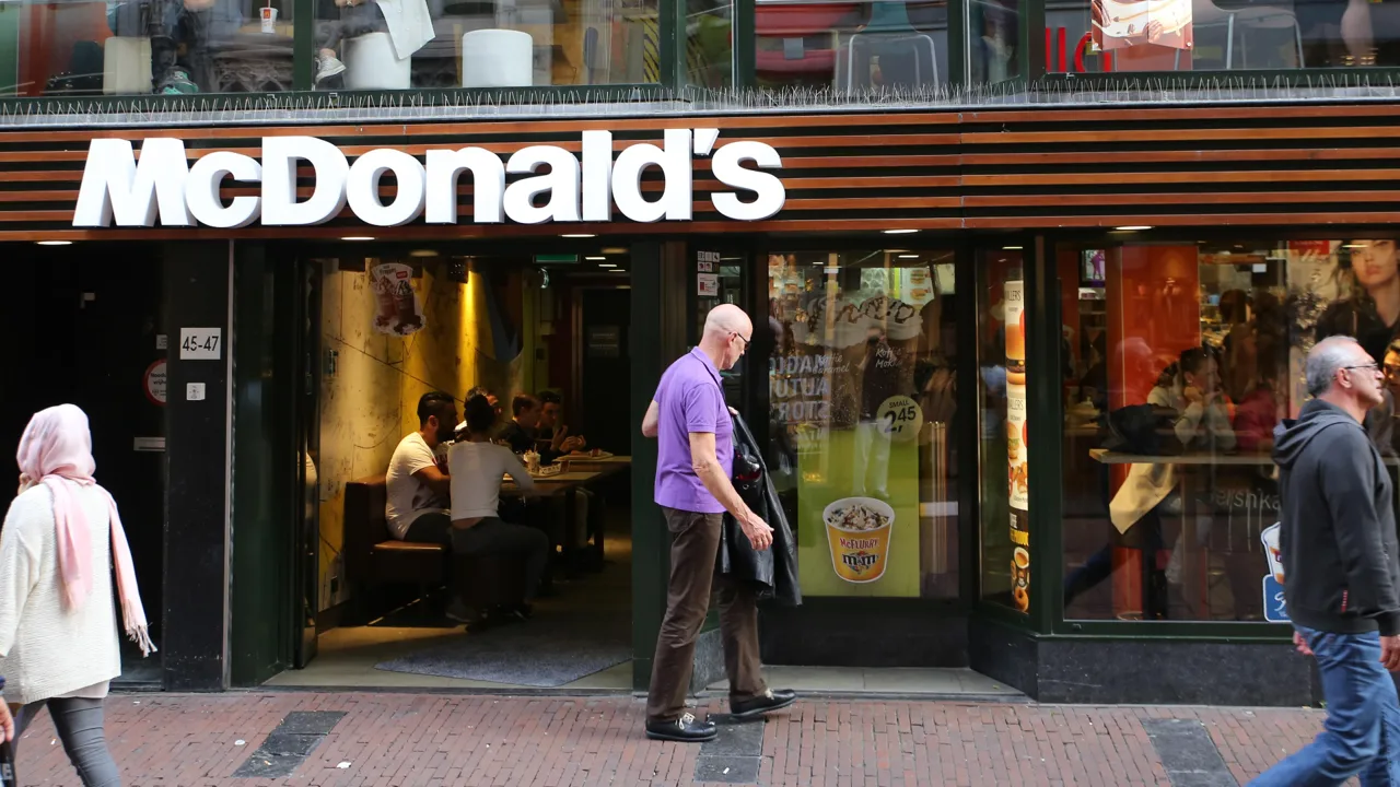 A McDonald's storefront on a city street with people walking by A McDonald's storefront on a city street with people walking by