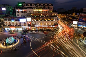 Hanoi intersection at night with trails of lights from traffic