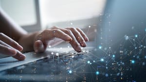 Two hands typing on a laptop's keyboard, with a digital overlay Two hands typing on a laptop's keyboard, with a digital overlay