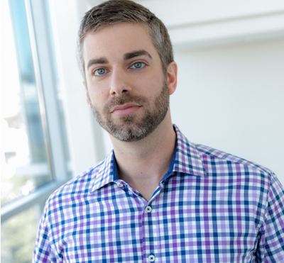 Brendan O'Connor, , CEO and Co-Founder, AppOmni, is a dark-haired bearded man wearing a blue plaid collared shirt