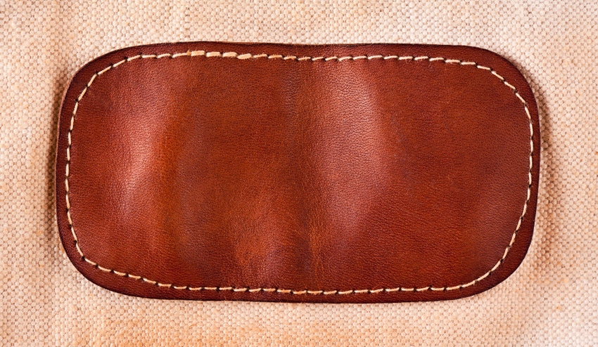 A brown leather patch sewn on fabric