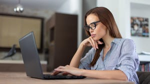 Young professional woman with glasses looking at laptop Young professional woman with glasses looking at laptop