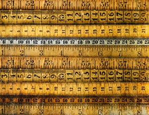 Antique rulers and measuring tapes lie horizontally across the image.