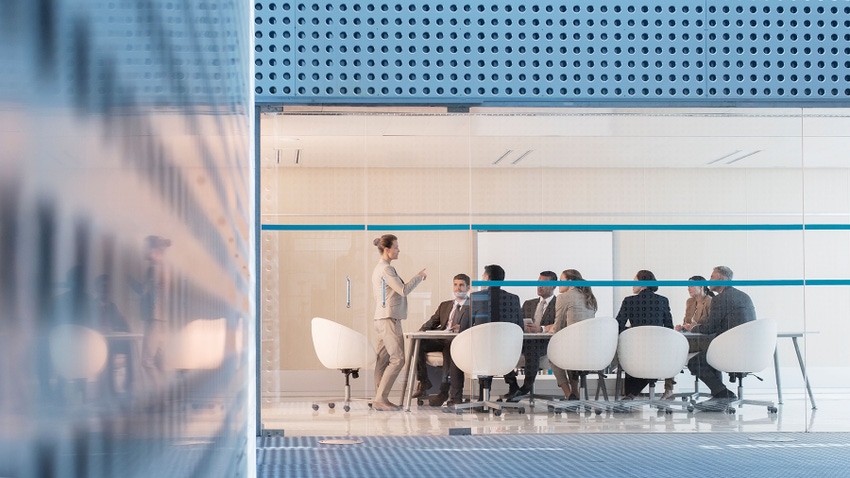 Businesswoman leading board meeting in modern conference room