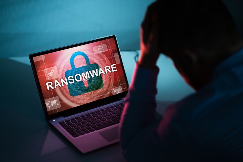 A laptop screen showing ransomware infection and a discouraged user with his head in his hand.